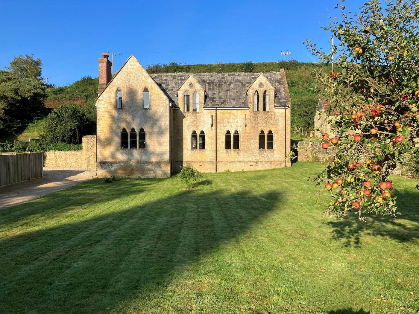 A stone building with a grassy lawn and a fruit tree.