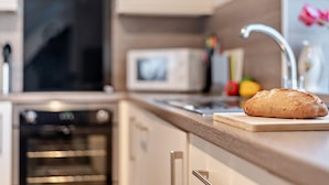 Eine Küche mit Mikrowelle, Backofen und einem Brotlaib auf der Arbeitsfläche.