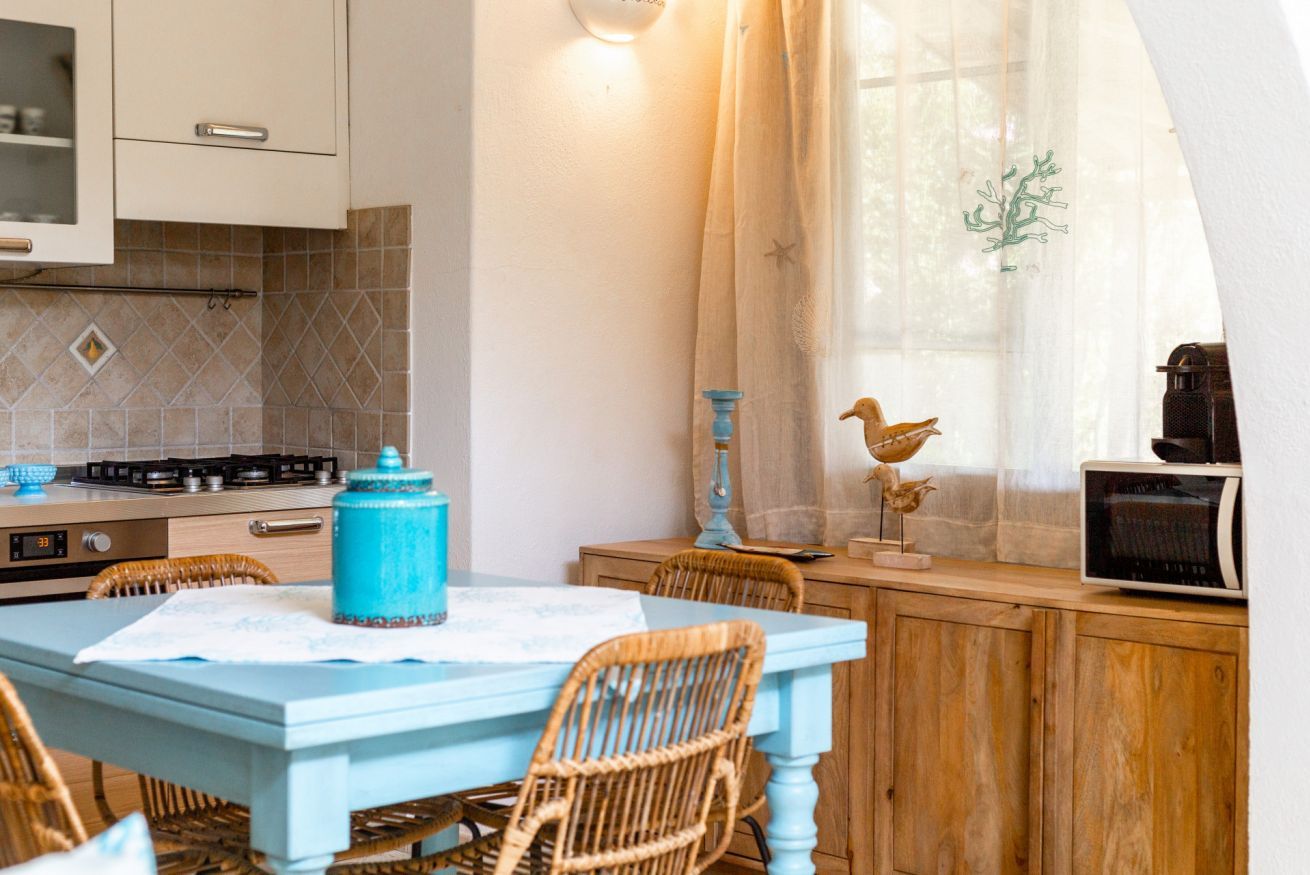 A kitchen with a blue table, wicker chairs, a stove, and a microwave.
