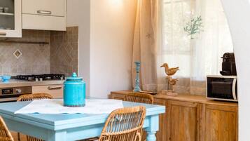 A kitchen with a blue table, wicker chairs, a stove, and a microwave.