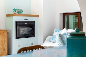 A room with a kitchenette, a wooden cabinet, a sofa with patterned cushions, and a window with curtains. - Sa Barchitta in Villasimius in the bay of Porto Luna (Villasimius)