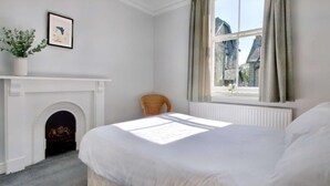 A bedroom with a bed, a fireplace, a window with curtains, and a framed picture on the wall. - 6 Bed in Keswick (oc-sz389) (Keswick)
