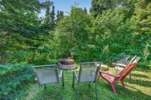 An outdoor seating area with a fire pit, two chairs, and a table. - Charlevoix Cabin | Hot Tub |Pool Table | 22 Guests (Petite-Rivière-Saint-François)