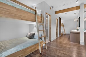 Une chambre moderne avec un lit superposé, une échelle en bois et un petit espace bureau.