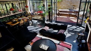 En moderne opholdsstue med spiseplads, sofa og stort vindue med udsigt over en have.