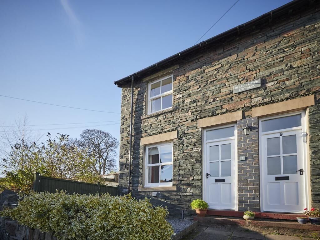 A stone building with two white doors and windows, labeled 'Belfry Green Cottages.'