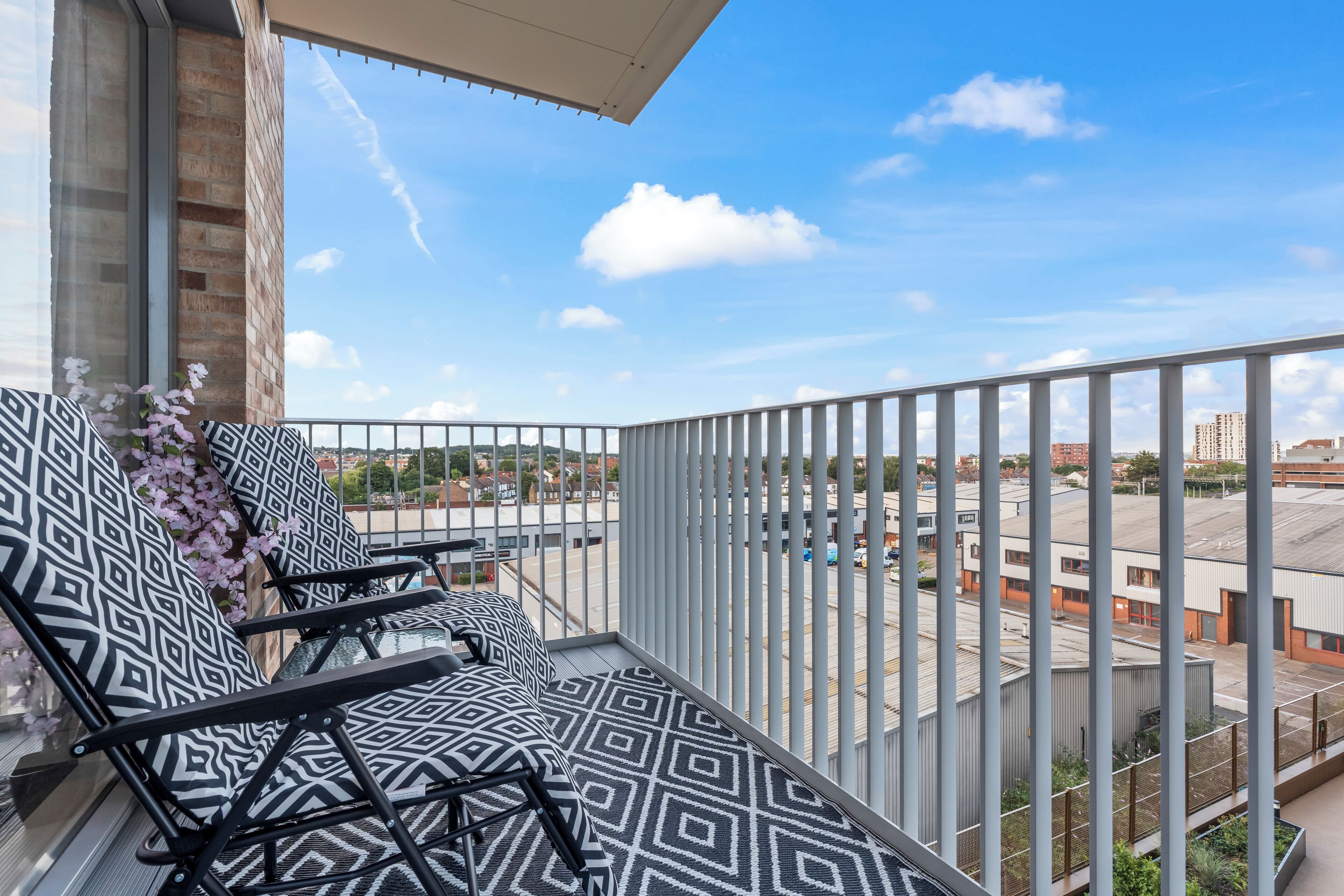 A balcony with patterned cushions, a railing, and a view of buildings.