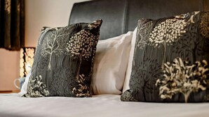 Un letto con due cuscini decorativi raffiguranti intricati disegni di alberi e foglie.