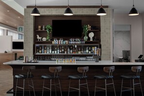 A modern bar area with a flat-screen TV, multiple liquor bottles, and bar stools.