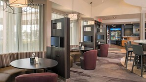 A hotel lobby with seating areas, a television, and a Pepsi refrigerator.