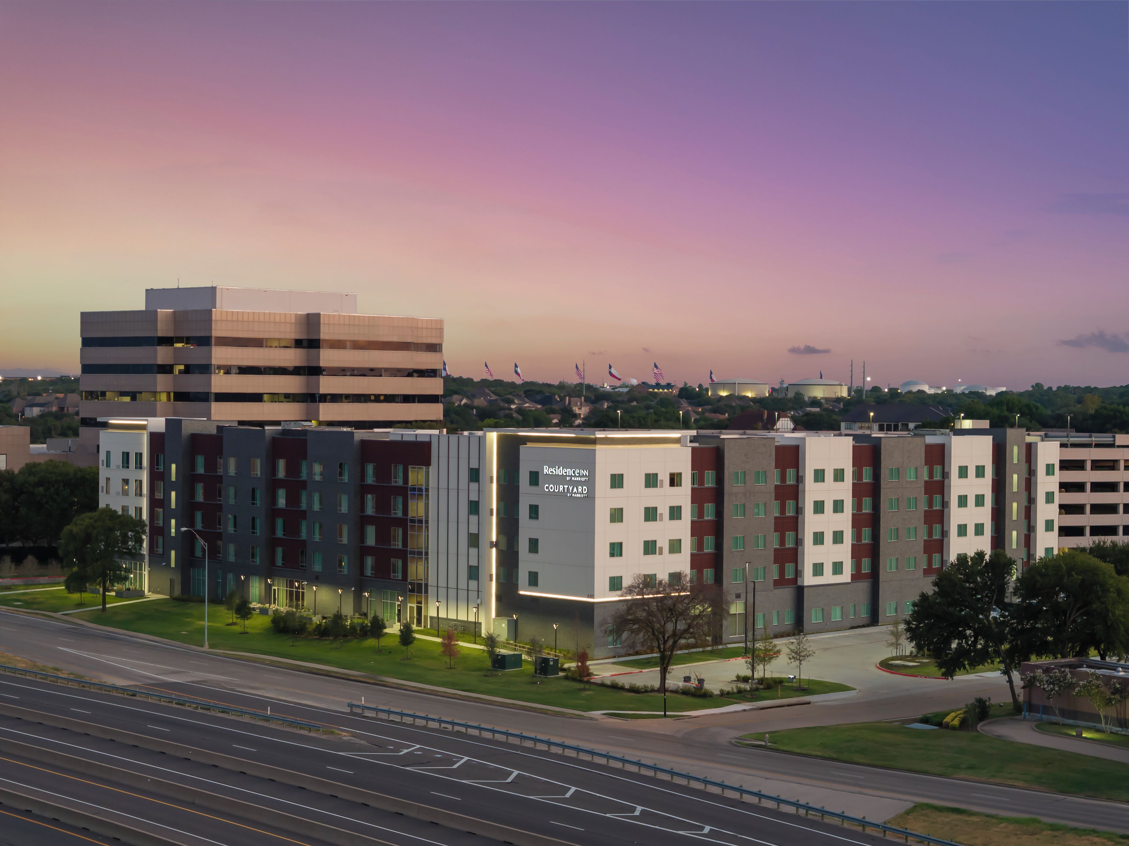 A multi-story hotel with a modern design, featuring a prominent entrance and a parking area.