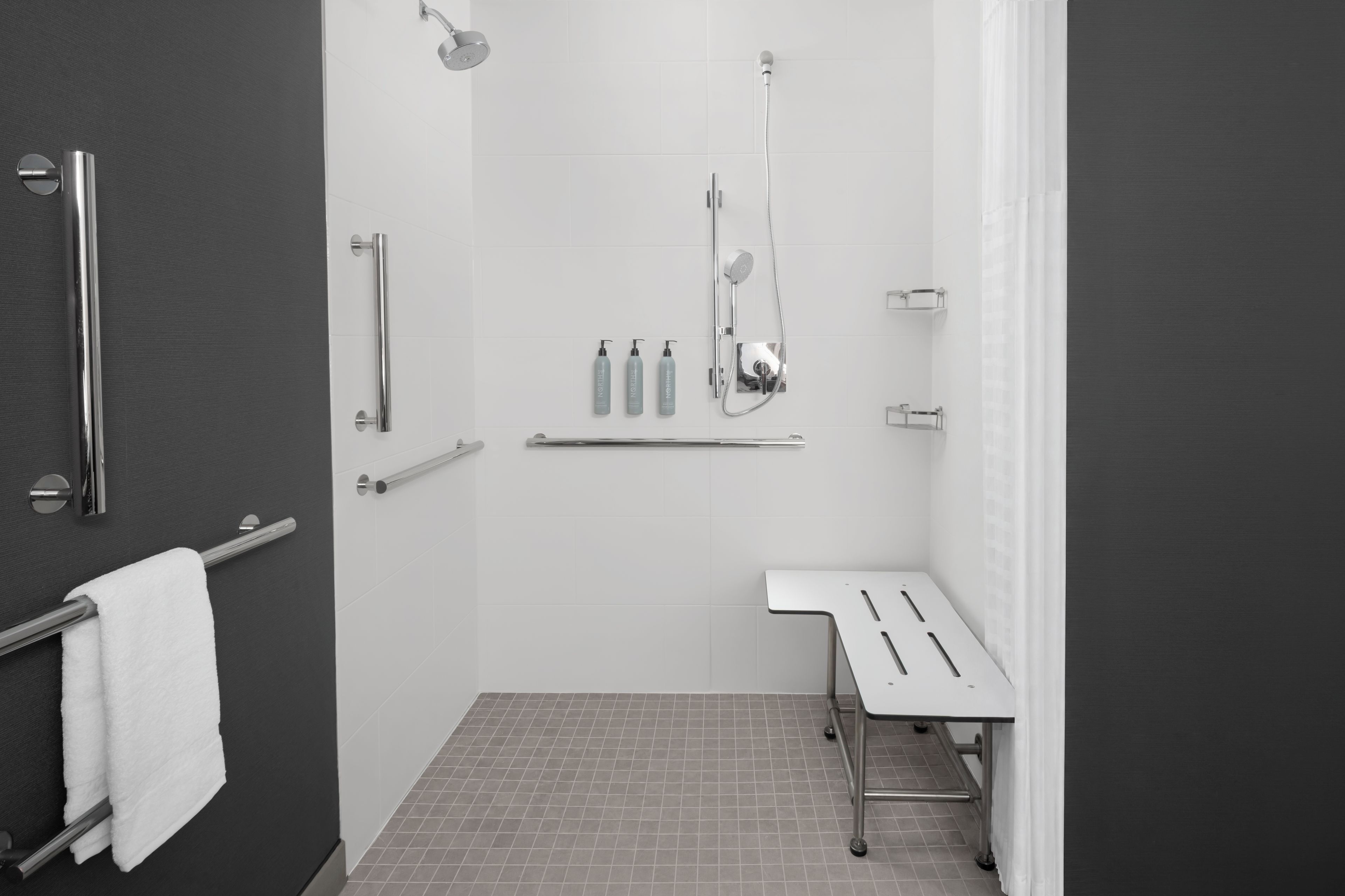 Un baño moderno con cabina de ducha, inodoro y un banco.