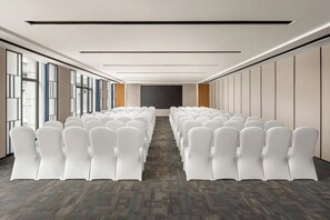 A conference room with rows of white chairs, a carpeted floor, and a large window on one side. - Fairfield By Marriott Zhoushan Daishan (Zhoushan)