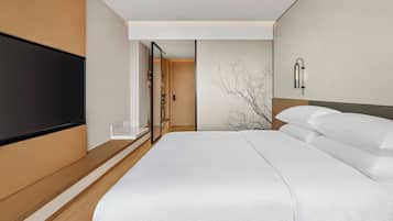 Een moderne hotelkamer met een groot bed, een flatscreen televisie aan de muur en een minimalistisch design.