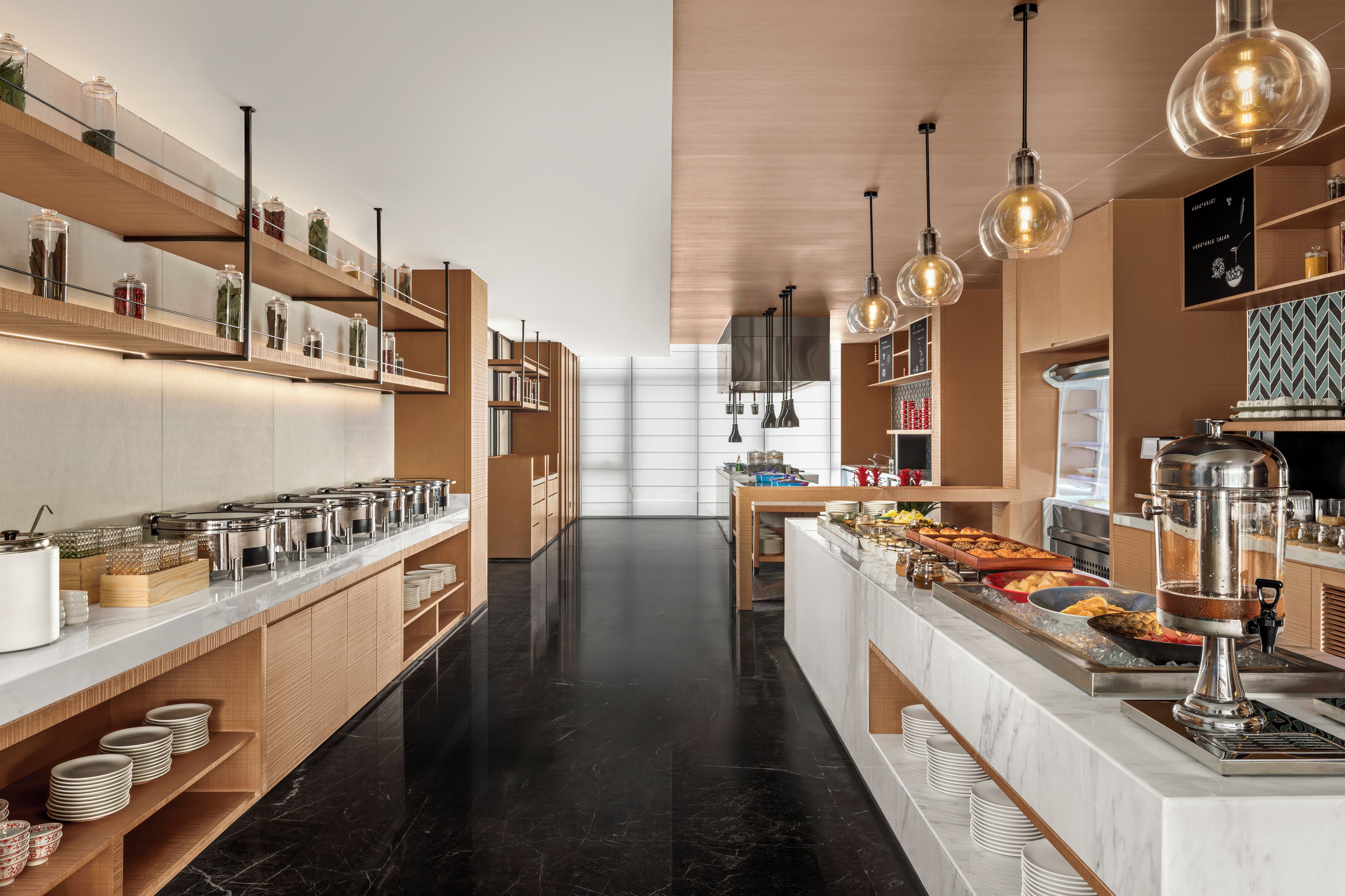Una cocina moderna con barra tipo bufé, electrodomésticos de acero inoxidable y estanterías de madera.