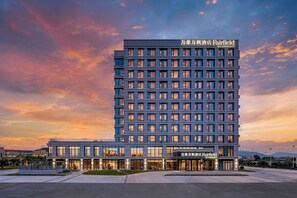 Un hotel de varios pisos con fachada moderna, ventanas amplias y techo plano.