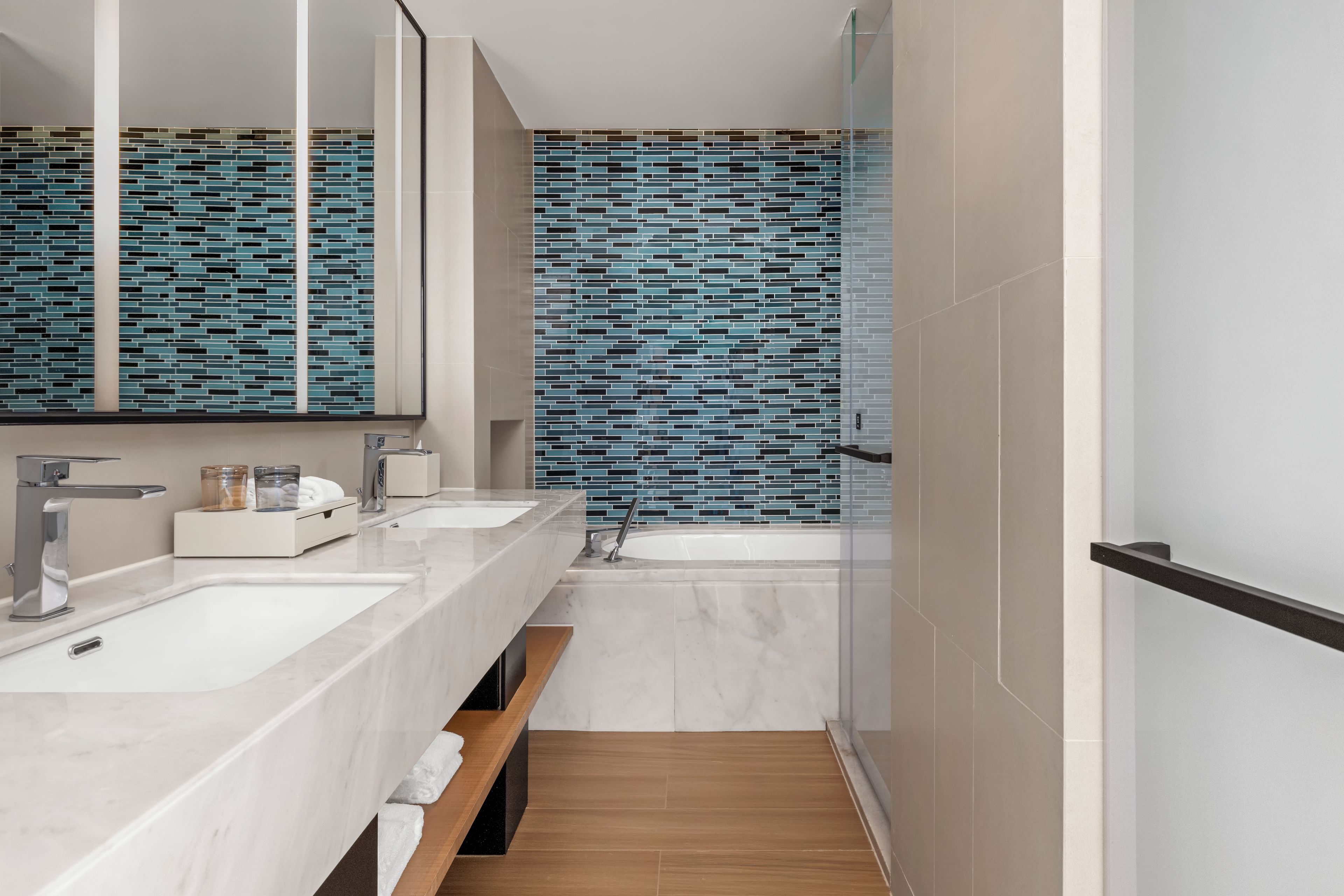 A modern bathroom with two sinks, a mirror, and a bathtub.