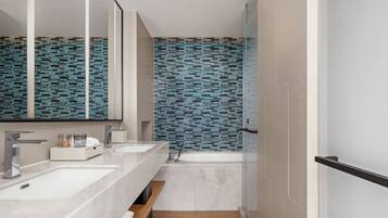 A modern bathroom with two sinks, a mirror, and a bathtub.
