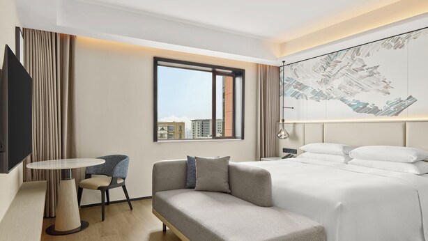 A hotel room with a bed, a sofa, a small table, and a chair.
