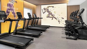 A gym with multiple treadmills, a motivational poster, and a large window.