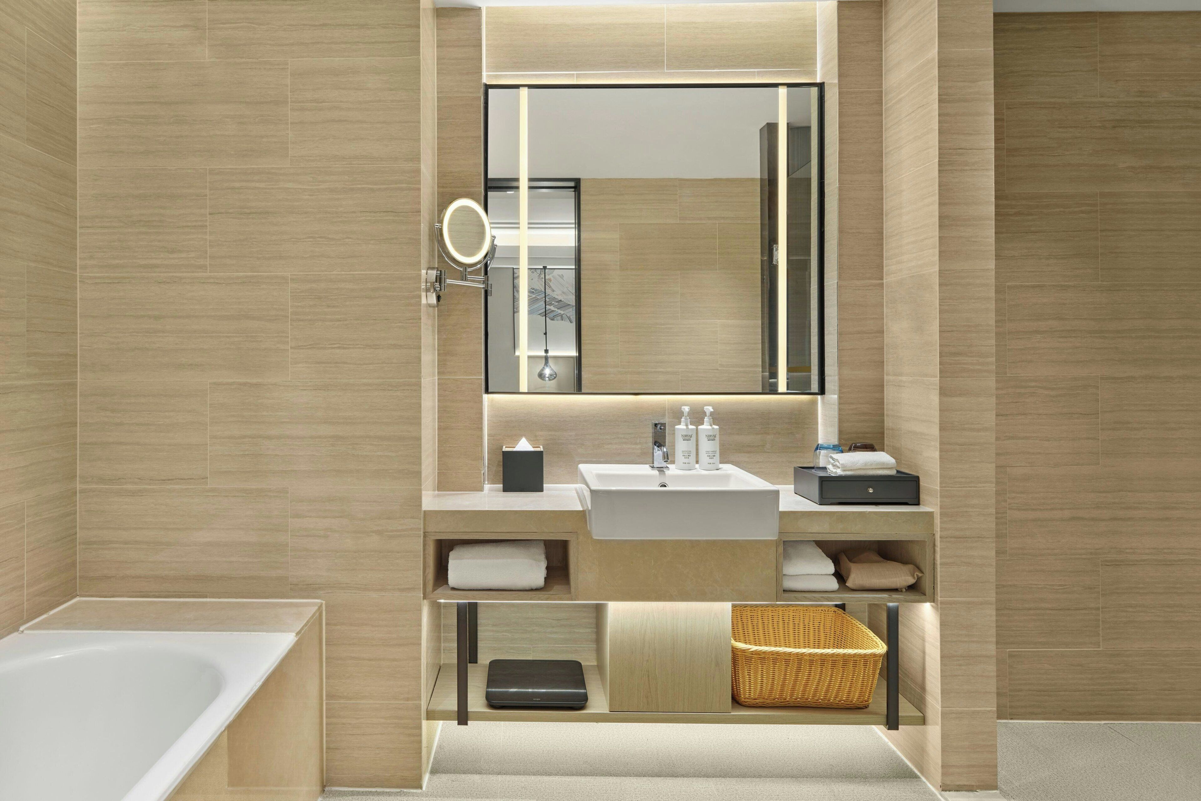A modern bathroom with a large mirror, a sink, and a bathtub.