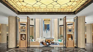 A spacious lobby with a geometric ceiling design, a central seating area, and modern furnishings.