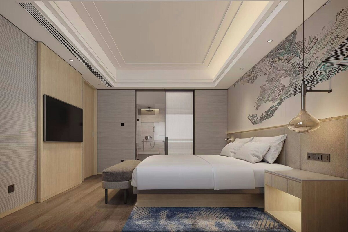 Un dormitorio moderno con cama, mesitas de noche, televisor, ducha y techo con diseño de hojas.