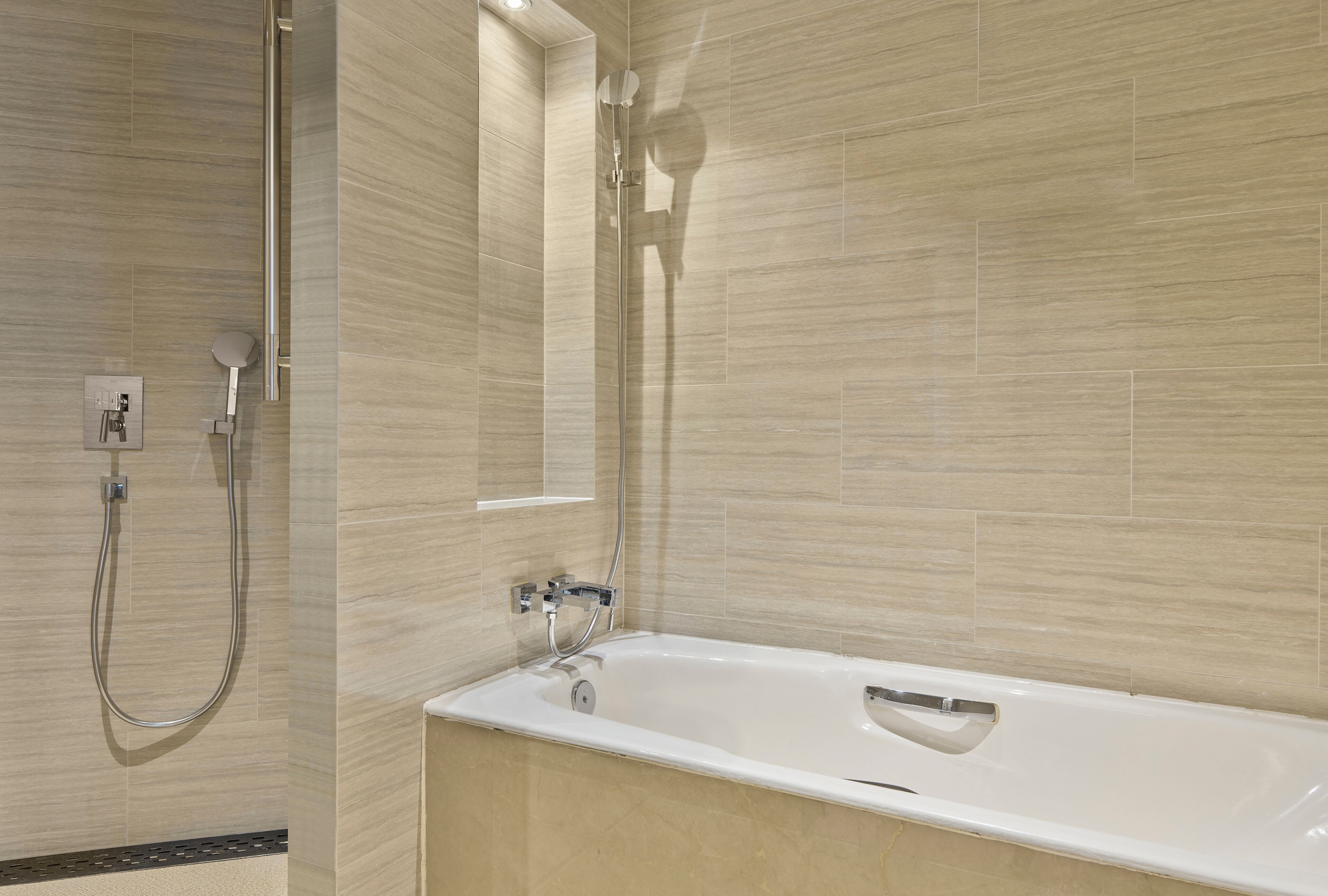 A modern bathroom with a bathtub, a shower area, and a wall-mounted mirror.
