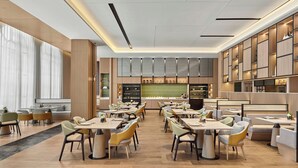 A modern restaurant interior with multiple dining tables and chairs, a kitchen area, and a bar.
