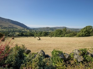 Paisaje rural con fardos de heno, colinas ondulantes y cielo despejado.