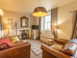 A cozy living room with a fireplace, leather sofas, a television, and a large mirror.