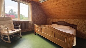 A room with a wooden ceiling, a bed, a rocking chair, a window, and a radiator. -  Villa & Timber Cabin’6,000 m² Estate Close to Lakes, Hiking, Cycling & Fishing (Västra Götalands län)
