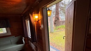 A wooden interior with a bench, a door leading outside, and two wall-mounted lights. -  Villa & Timber Cabin’6,000 m² Estate Close to Lakes, Hiking, Cycling & Fishing (Västra Götalands län)