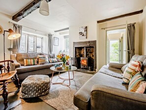 Una sala de estar acogedora con chimenea, un sofá, una mesa de centro y una lámpara.