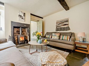 A cozy living room with a fireplace, a sofa, a coffee table, and a lamp.