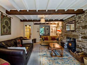 Una sala de estar acogedora con chimenea de piedra, un sofá de cuero, una mesa de centro de madera y un tapete estampado.