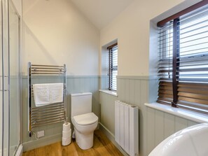 Un baño con inodoro, toallero, radiador y ventana con persianas.