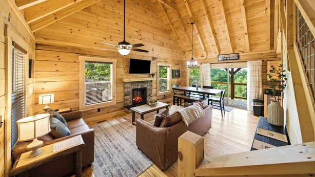 A log cabin interior with a fireplace, wooden furniture, and a dining area. - New Build Cabin! Close to Mountains, Dollywood, Parkway, Pigeon Forge (Pigeon Forge)