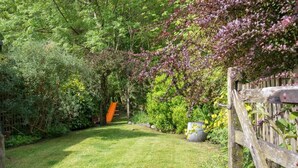 A garden with a wooden fence, a grassy lawn, and various plants. - 2 Bed in Keswick (oc-sz068) (Borrowdale)