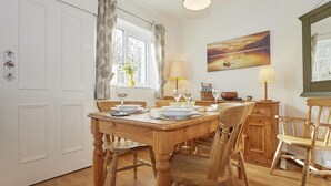 A dining area with a wooden table, chairs, a chandelier, and a painting on the wall. - 2 Bed in Keswick (oc-sz068) (Borrowdale)