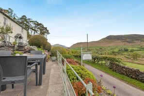 Eine Terrasse mit Gartenmöbeln, einer Steinmauer und Blick ins Grüne.