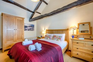 A bedroom with a wooden wardrobe, a bed with a red bedspread, a wooden nightstand with a lamp, and a mirror on the dresser. - 3 Bed in Borrowdale (oc-sz465) (Borrowdale)
