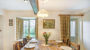 A dining room with a wooden table set for four, a vase of flowers, and a painting on the wall. - 3 Bed in Cumbria (oc-sz101) (Crosthwaite and Lyth)