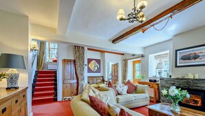 Uma sala de estar ampla com tapete vermelho, lareira, escada e um espaço de estar aconchegante.