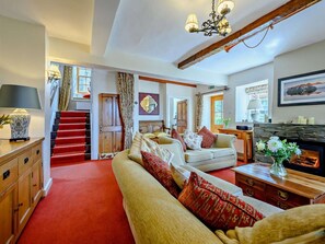 A spacious living room with a red carpet, a fireplace, a staircase, and a cozy seating area. - 4 Bed in Keswick (oc-sz120) (Keswick)