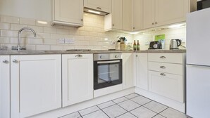 A kitchen with white cabinets, a stainless steel sink, a built-in oven, and a refrigerator. - 2 Bed in Keswick (oc-sz009) (Keswick)