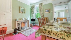 A dining room with a fireplace, a television, and a dining table set for four. - 3 Bed in Keswick (oc-sz395) (Keswick)