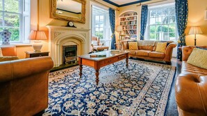 A traditional living room with a fireplace, leather sofas, a coffee table, and a bookshelf. - 5 Bed in Keswick (oc-sz359) (Keswick)