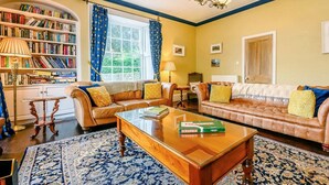 A living room with a sofa set, a coffee table, a bookshelf, and a chandelier. - 5 Bed in Keswick (oc-sz359) (Keswick)