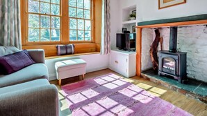 A cozy room with a large window, a fireplace, a sofa, and a television. - 1 Bed in Keswick (oc-sz472) (Keswick)